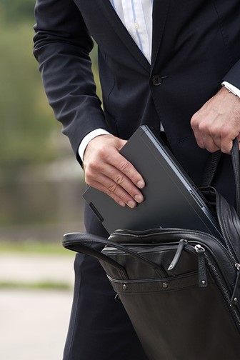 businessperson placing a laptop computer into a leather laptop case